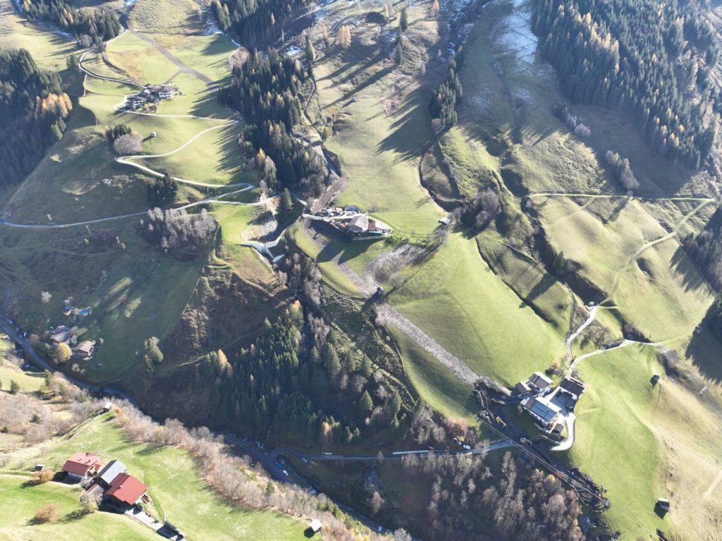 Aussicht auf die grüne Landschaft der Region Rauris mit verstreuten Gebäuden.